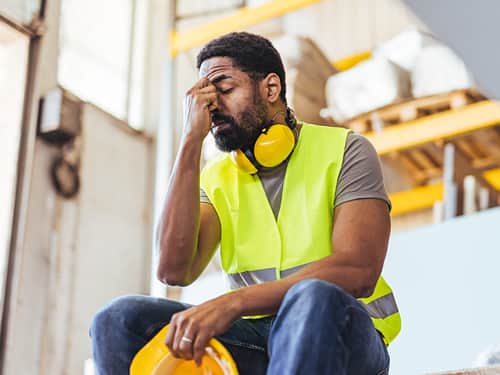 A man has his head in his hands, suggesting feelings of sadness and frustration.