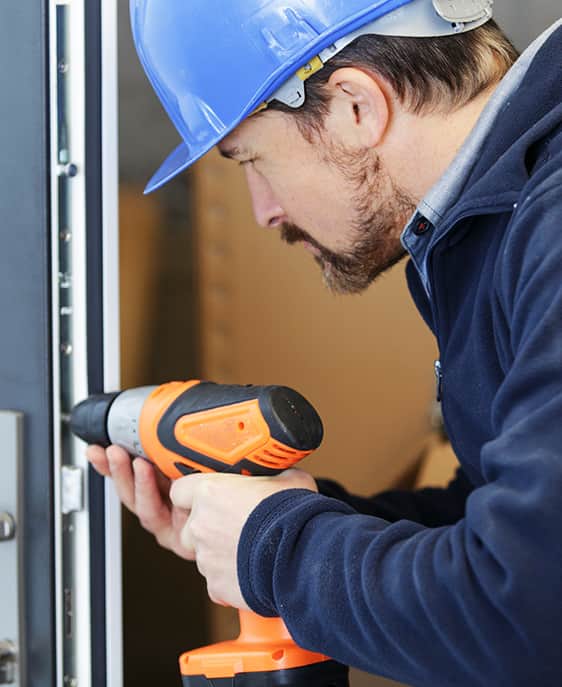 A man is engaged in fixing a door with a drill, showcasing practical maintenance work.
