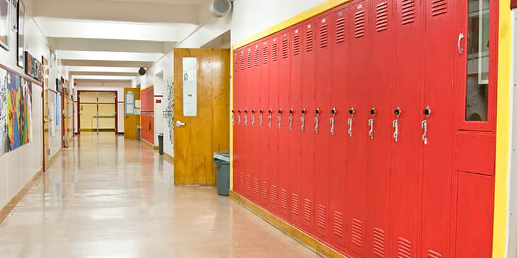 An empty school hallway featuring bright yellow walls and rows of red lockers lining both sides.