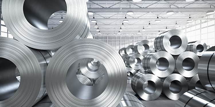 A large group of rolled steel stacked neatly in a warehouse setting.